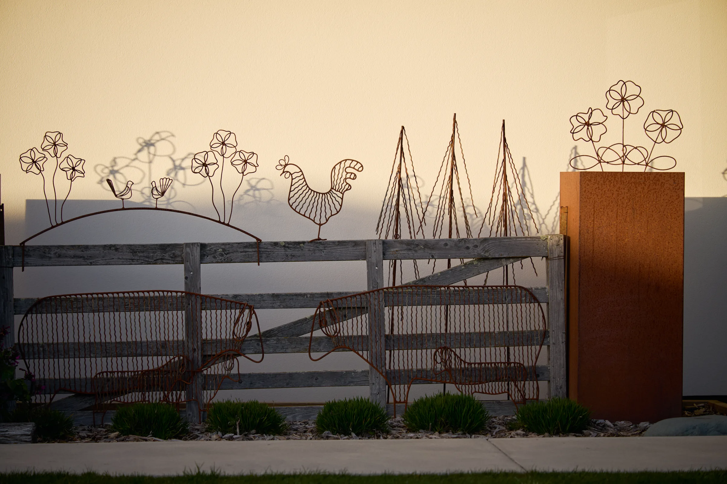 Wire flowers by the same maker, against a rusted steel panel.