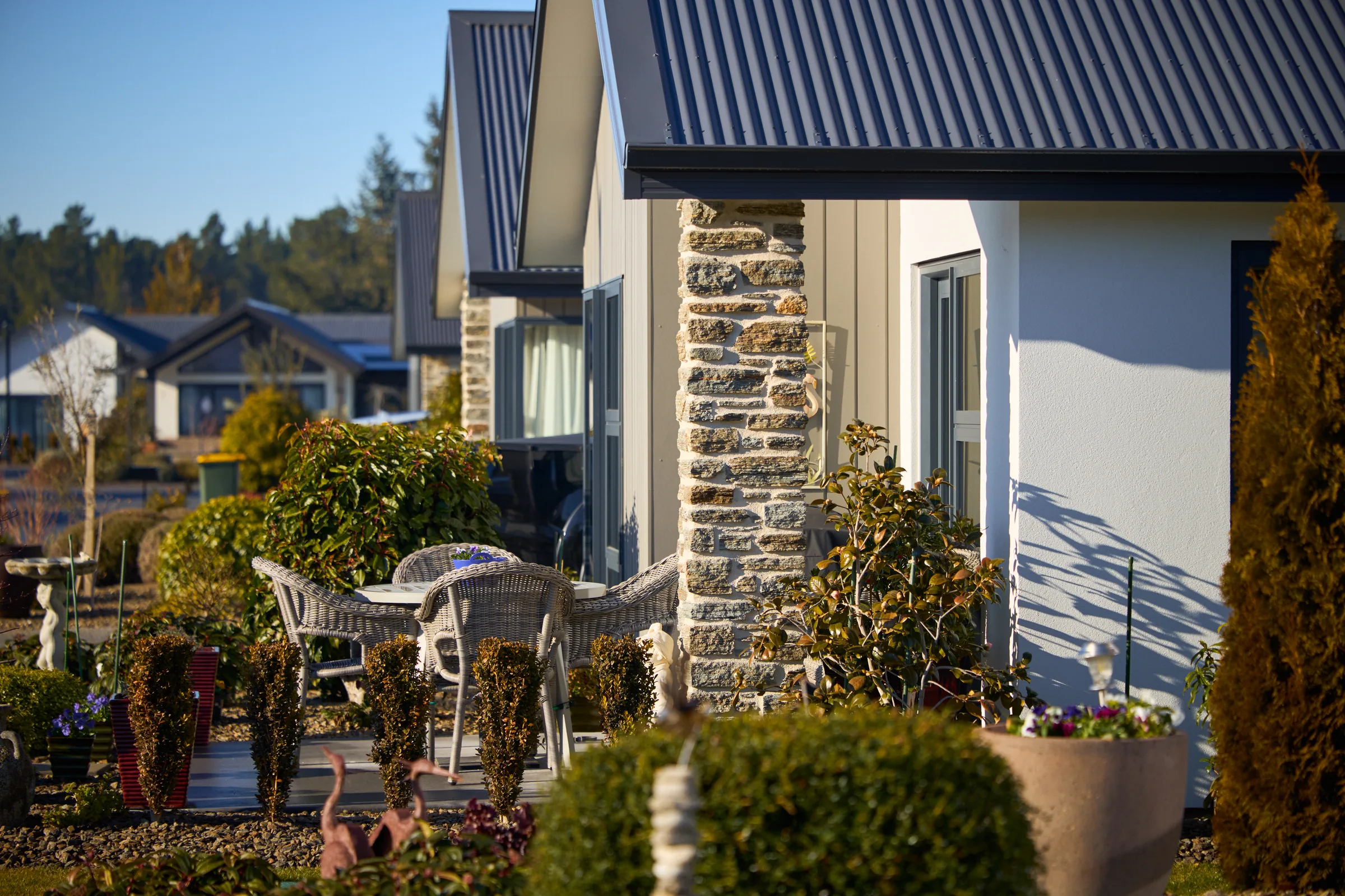 A paved courtyard with a resident's own garden ornaments set out on it.