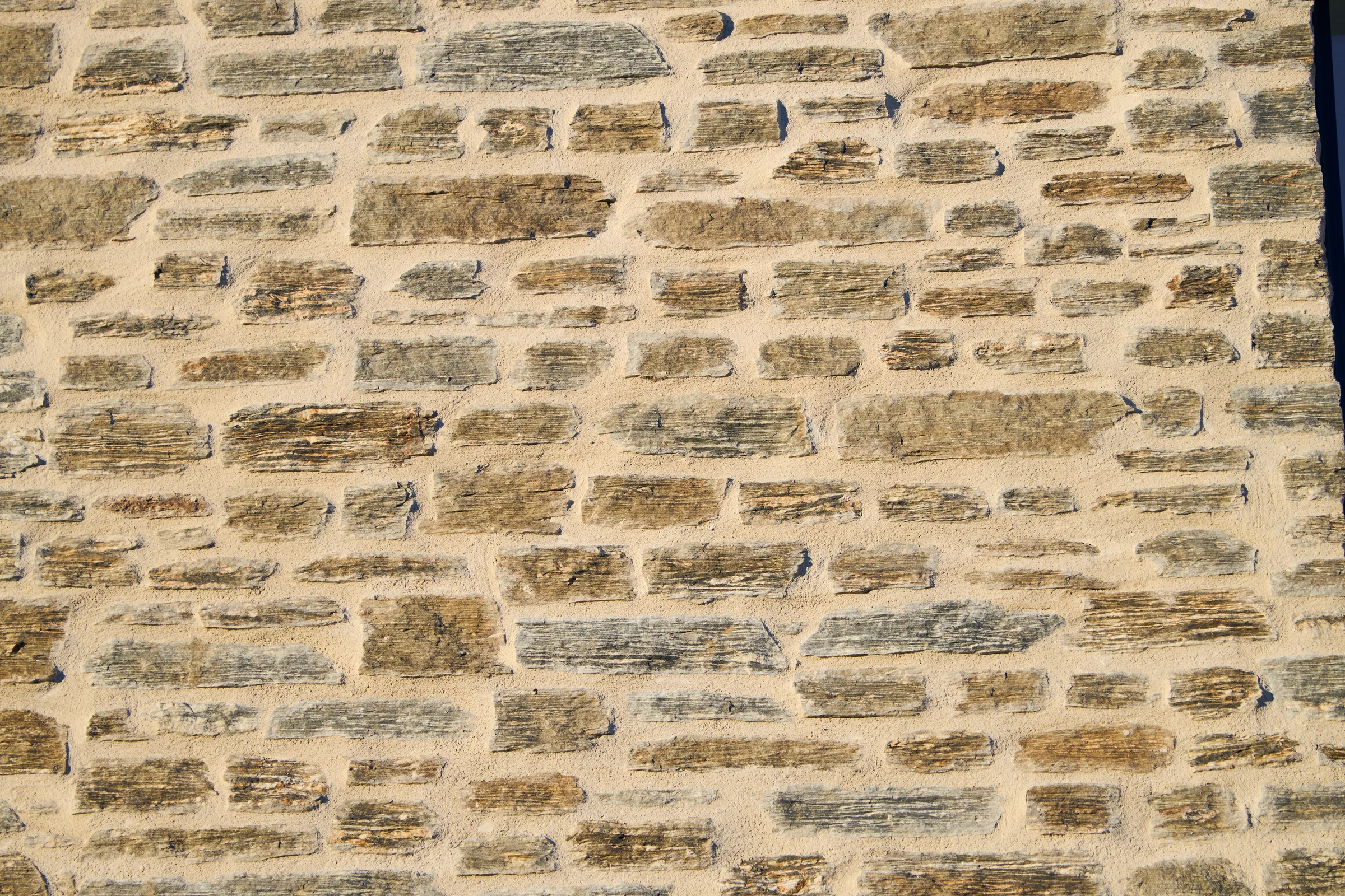 Coursed schist against cream mortar, filling the frame.