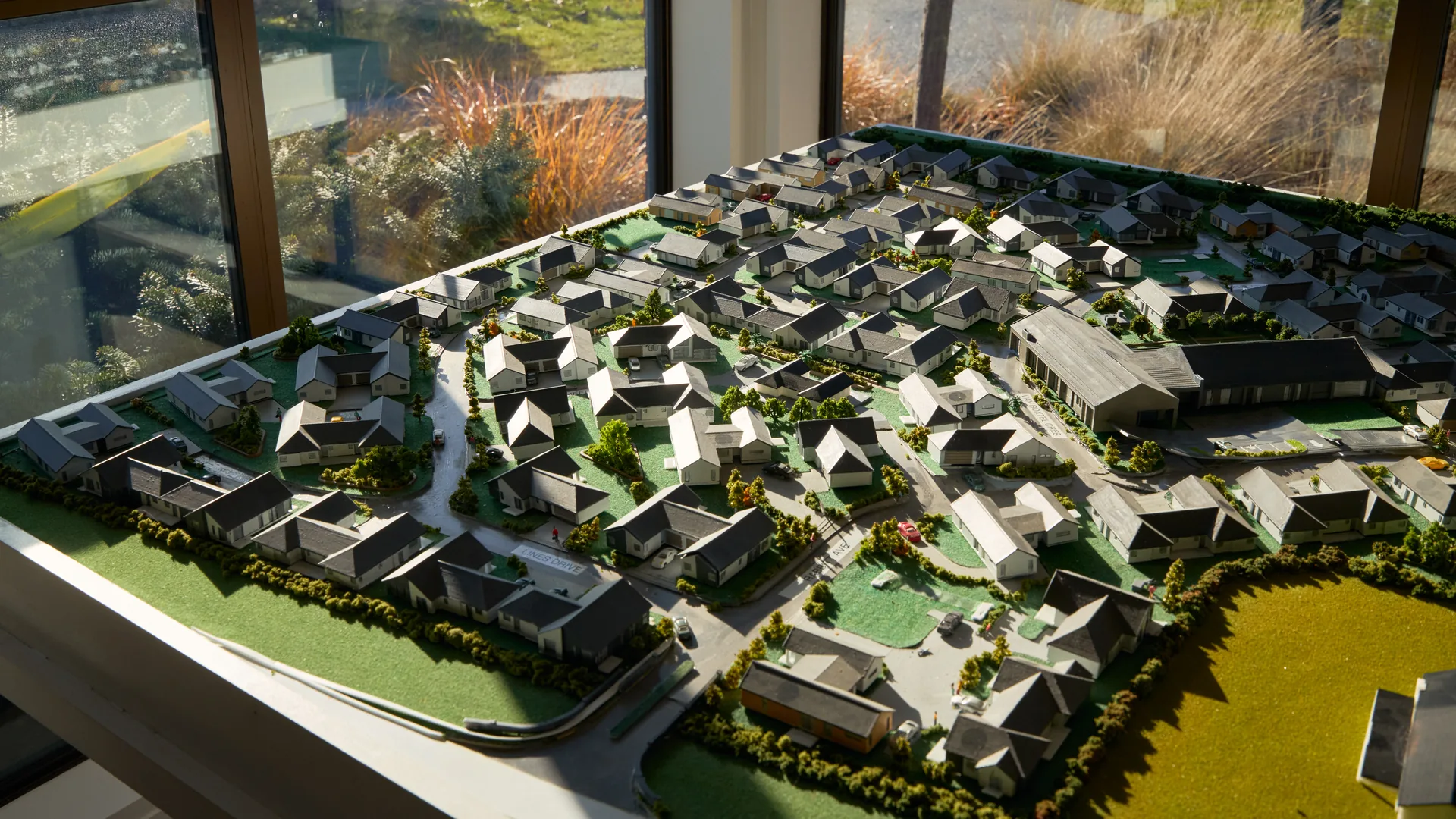 A scale model of a village masterplan on a table, with villas, streets and planting laid out in miniature.